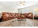 Inviting living room featuring a comfortable brown leather sectional, ceiling fan, and a stylish round rug at 11072 Pebble Ridge Dr, Hampton, GA 30228