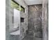 Modern shower with gray marble walls, a built-in bench, and a rainfall shower head at 2709 Collins Hill Rd, Lawrenceville, GA 30043