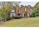 Charming two-story brick home with well-manicured landscaping, shutters, and an American flag at 3565 Hickory Branch Trl, Suwanee, GA 30024
