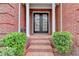 Inviting front entrance with brick steps, black double doors, trimmed bushes, and brick walls at 3565 Hickory Branch Trl, Suwanee, GA 30024