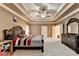 A main bedroom featuring a tray ceiling, ceiling fan, carpeted floors, and a door to the bathroom and closet at 3565 Hickory Branch Trl, Suwanee, GA 30024