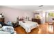 A well-lit bedroom with an ornate bed frame, wood floors, and a window at 4256 Village Square Ln, Stone Mountain, GA 30083