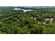 Aerial view of a home surrounded by lush greenery with the lake in the background at 2709 Windrush Dr, Buford, GA 30518