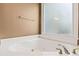 Relaxing bathroom featuring a soaking tub with jets and a frosted glass window for natural light and privacy at 2709 Windrush Dr, Buford, GA 30518