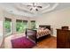 Main bedroom boasts a trey ceiling, hardwood floors, and large windows offering serene backyard views at 2709 Windrush Dr, Buford, GA 30518