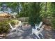 Backyard with a fire pit and four chairs, surrounded by trees and bushes with a partial fence at 3837 Fenway Xing, Marietta, GA 30062