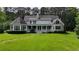 Expansive backyard view of a home with a full-length porch, showcasing lush greenery and outdoor living space at 625 W Lake Dr, Oxford, GA 30054