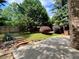 Backyard featuring mature trees, stone steps, hardscape patio, and outdoor kitchen at 5220 Wild Cedar Dr, Buford, GA 30518