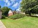 Lush front yard of a brick home with an attached two-car garage and mature shade tree at 5220 Wild Cedar Dr, Buford, GA 30518