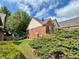 Side view of brick home with manicured lawn, established shrubs, and trees at 5220 Wild Cedar Dr, Buford, GA 30518