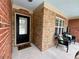 Inviting brick front porch with seating, a decorative welcome sign, and black front door at 5220 Wild Cedar Dr, Buford, GA 30518