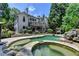 Backyard view featuring a luxurious spa and swimming pool with stone details, surrounded by tall trees at 7920 Tintern Trce, Duluth, GA 30097
