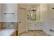 Bright bathroom features a bathtub, vanity with marble countertops, decorative light fixture, tile floors, and a window at 7920 Tintern Trce, Duluth, GA 30097