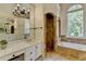 Bright bathroom features a bathtub, shower, vanity with marble countertops, and a decorative light fixture at 7920 Tintern Trce, Duluth, GA 30097