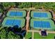 Aerial view of four well-maintained tennis courts with lush landscaping, lighting, and viewing areas at 7920 Tintern Trce, Duluth, GA 30097