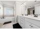 Elegant bathroom with double sinks, marble countertops, white cabinets, and a soaking tub at 3865 Brookhollow Dr, Douglasville, GA 30135