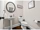 Half bathroom features a modern pedestal sink, toilet, and round decorative mirror at 3865 Brookhollow Dr, Douglasville, GA 30135