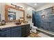 Bathroom featuring modern vanity, wood-framed mirror, stylish blue tiled shower, and wood-look flooring at 414 Silver Top Dr, Grayson, GA 30017