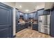 Charming kitchen boasts stainless appliances, stone counters, brick backsplash, and stylish blue cabinetry at 414 Silver Top Dr, Grayson, GA 30017