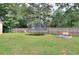 Expansive backyard featuring playset, trampoline and open green space with a fire pit and fenced perimeter at 1050 Kirkland Rd, Covington, GA 30016