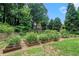 Lush backyard featuring manicured lawn, garden beds, and mature trees, creating a serene outdoor oasis at 265 Lee River Cv, Suwanee, GA 30024