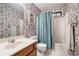 Bathroom featuring patterned wallpaper, single sink vanity, and shower-tub combo at 265 Lee River Cv, Suwanee, GA 30024