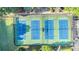 Aerial view of well-maintained blue tennis courts with parking and surrounded by lush greenery at 265 Lee River Cv, Suwanee, GA 30024