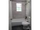 This bathroom showcases a shower-tub combination with stylish dark fixtures against light stone-patterned tiles at 3086 Lone Oak Sw Ave, Atlanta, GA 30354