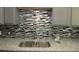 Close up of a stainless steel kitchen sink with granite countertops and a mosaic tile backsplash at 3086 Lone Oak Sw Ave, Atlanta, GA 30354