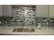 Close up of the kitchen sink, faucet, mosaic backsplash and gray cabinets at 3086 Lone Oak Sw Ave, Atlanta, GA 30354
