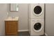 This laundry room has a stackable washer and dryer, gray walls, and a sink with wooden cabinetry at 3086 Lone Oak Sw Ave, Atlanta, GA 30354