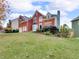 Red brick two-story home with attached two-car garage, landscaped lawn and mature trees at 3195 Vickery Dr, Marietta, GA 30066