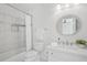 Bright bathroom featuring a shower-tub combo with white tile and a round vanity mirror at 230 Summerhouse Ln, Atlanta, GA 30350
