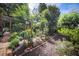 Lush backyard featuring lantern lighting, garden beds with flowers, and a tranquil escape into nature at 176 Oakland Way, Dallas, GA 30157