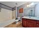 Well-lit bathroom featuring a combination tub and shower, along with a cherry cabinet sink at 176 Oakland Way, Dallas, GA 30157