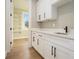 A well-lit laundry room with white cabinetry, a sink, and hardwood floors at 2200 Upper Burris Rd, Canton, GA 30114