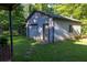 Exterior of detached garage with a single-car garage door and side entrance, surrounded by a lush green yard at 4370 Tradition Ter, Austell, GA 30106