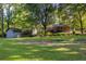 Expansive backyard featuring a well-maintained lawn, mature trees, detached garage, and covered patio at 4370 Tradition Ter, Austell, GA 30106