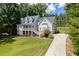 A traditional two-story home features a welcoming front porch, well-manicured lawn, and a long driveway in a serene setting at 5178 Stefan Ridge Way, Buford, GA 30519