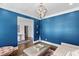 Stylish living room with blue walls, an elegant light fixture, and an open doorway to other rooms at 5178 Stefan Ridge Way, Buford, GA 30519