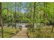 View of the private tennis court with a deck and surrounded by a lush, green landscape at 5251 Powers Ferry Rd, Atlanta, GA 30327