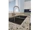 Close up of a stylish kitchen featuring a stainless steel sink, granite countertops and new fixtures at 10900 Wittenridge Dr # H8, Alpharetta, GA 30022