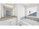 Bright bathroom featuring double sinks, granite countertops, and a soaking tub with a window at 11854 Rizvan Pl, Covington, GA 30014