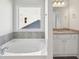 Bright bathroom featuring a soaking tub with tile accents and double vanity with granite countertops at 11854 Rizvan Pl, Covington, GA 30014