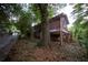 View of elevated red home with partial stone foundation surrounded by foliage and a chain-link fence at 1398 Christmas Ne Ln, Atlanta, GA 30329