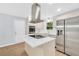 Modern kitchen with stainless steel appliances, kitchen island with cooktop, marble countertops, and a window at 3355 Wesley Chapel Rd, Decatur, GA 30034