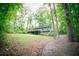 Exterior view of a single Gathering home with a deck surrounded by mature trees and lush greenery at 4190 Heather Way, Cumming, GA 30041