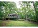 Exterior view of a single Gathering home with a deck surrounded by mature trees and lush greenery at 4190 Heather Way, Cumming, GA 30041