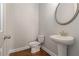 Modern powder room features a pedestal sink, decorative mirror, and wood look flooring at 3139 Hilltop Drive, Marietta, GA 30066