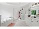 All-white bathroom features tile floors, a glass-enclosed shower, soaking tub, and dual sinks at 6219 Creekstone Path, Cumming, GA 30041
